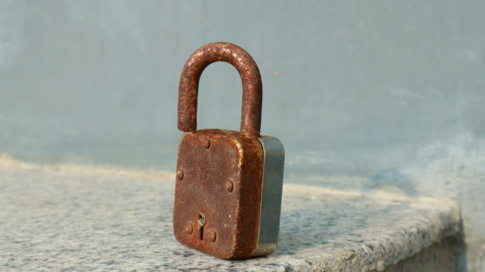 A rusty padlock sitting on top of a stone wall